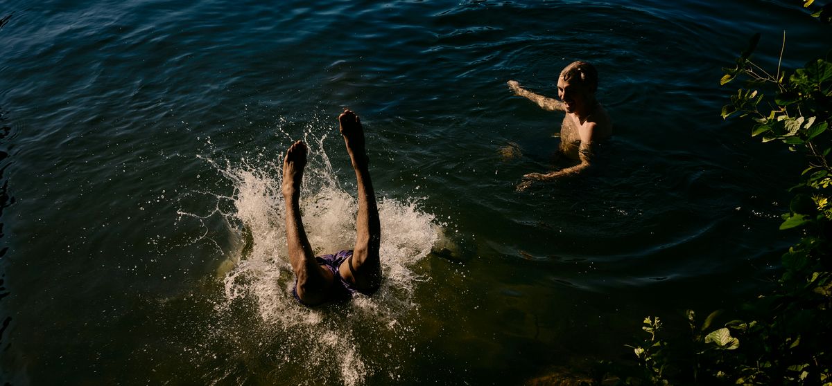 Two people playing in a body of water with one person diving in.