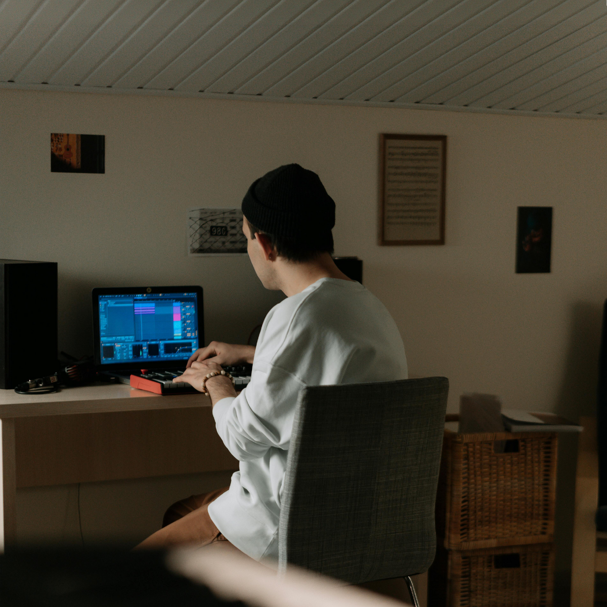 Person sitting at a desk using a computer in a dimly lit room.